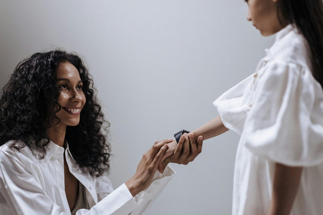 Mother and daughter smiling while setting up a KidBand⢠smartwatch for kids' safety and connection.